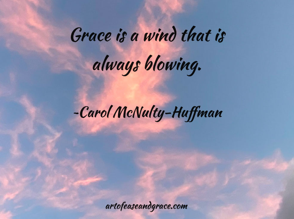 The sun is behind pink clouds with an orange tinge. The sky is blue. There is a quote on the picture: "Grace is a wind that is always blowing." By Carol McNulty-Huffman