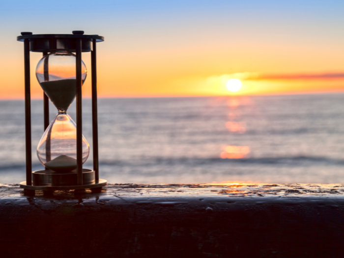 Hour Class on a Railing Overlooking the Ocean View with Sun Setting Over Ocean